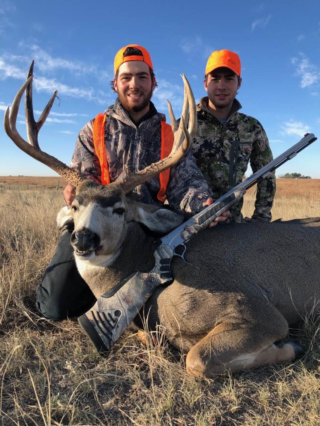 Two hunters with a mule deer buck at day's end