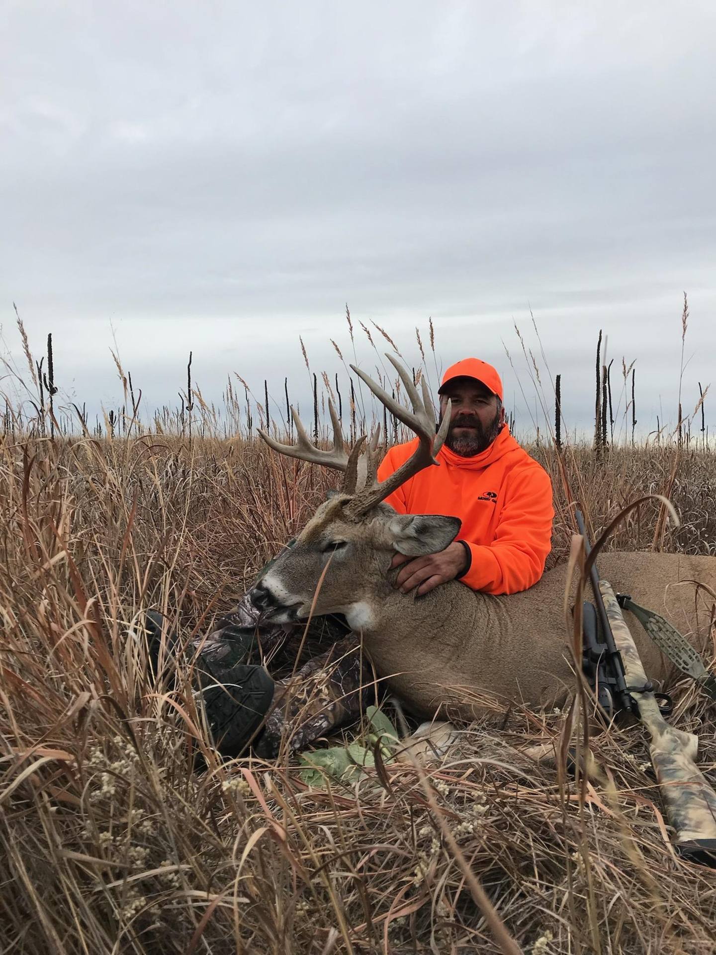 Hunter with a whitetail buck in tall prairie grass