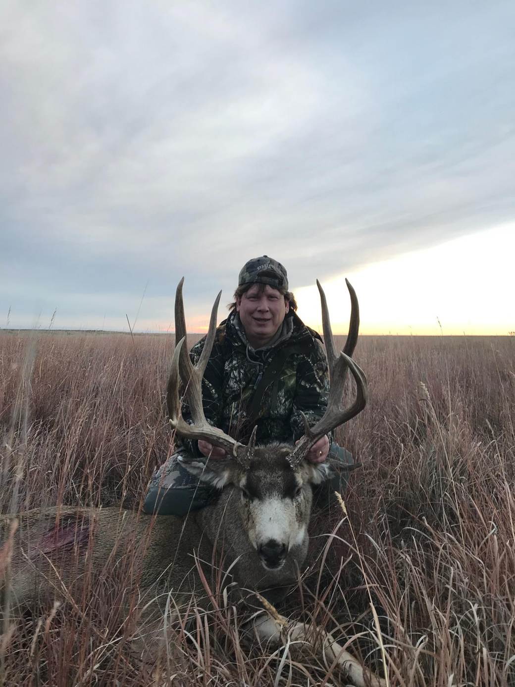 Hunter with a whitetail buck on the open prairie